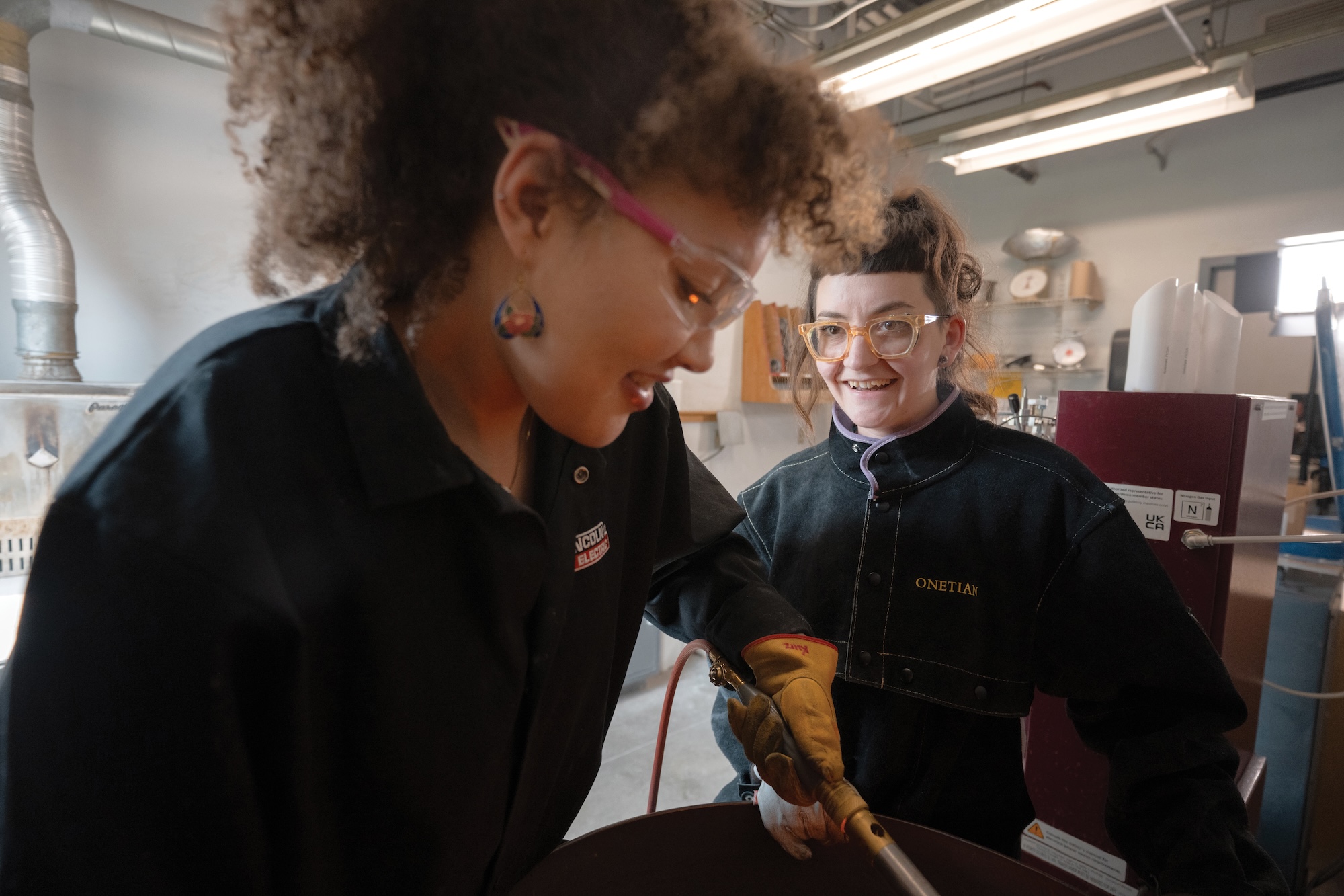 Student casting metal and working in the Metals Studio with instructor