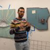 A student standing in front of paintings in a studio