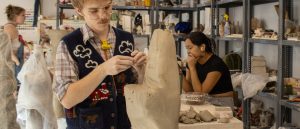 A ceramics student works on a large scale piece in the studio during class