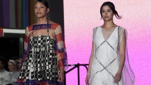 two models walking down the runway. the model on the left is wearing a multicolor patterned dress, while the model on the right is wearing a white and grey dress