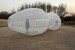 Kendall Buster's sculpture, two linked orbs made of metal frame and transparent white cloth. A person stands inside the sculpture.