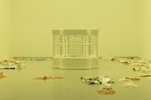 A the exterior section of a house's sunroom stands in the center of an empty room. The floor of the room has small piles of fabric pieces.